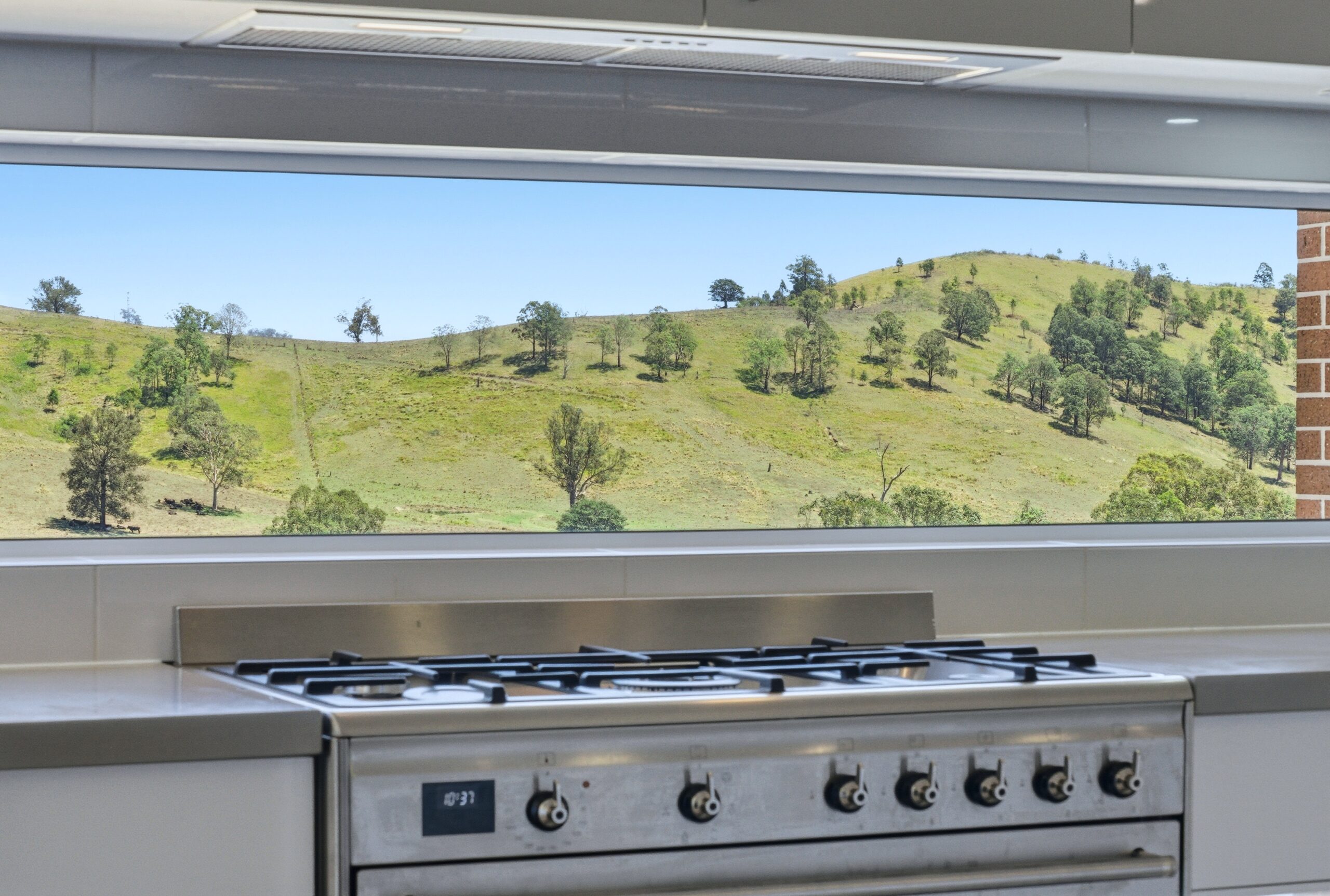 Gas cooktop with panoramic hill views through the kitchen splashback window at Florence Talbot House